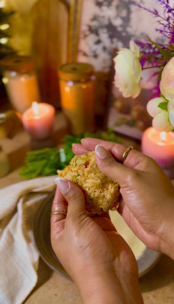 A close-up of hands shaping a salmon patty, with candles, flowers, and decorative items in the background.