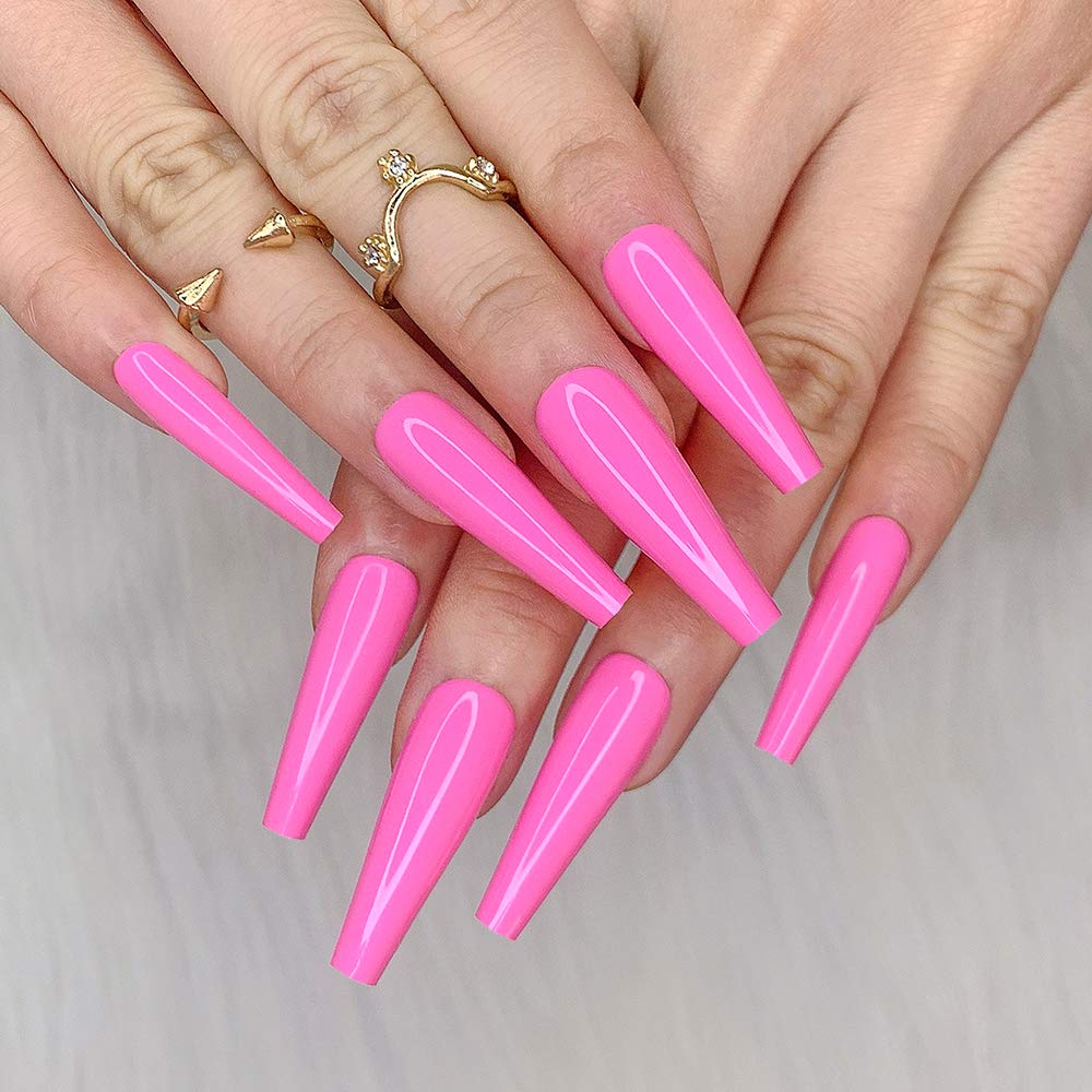 Close-up of hands with long, pointed pink nails and gold rings, showcasing a stylish nail design.