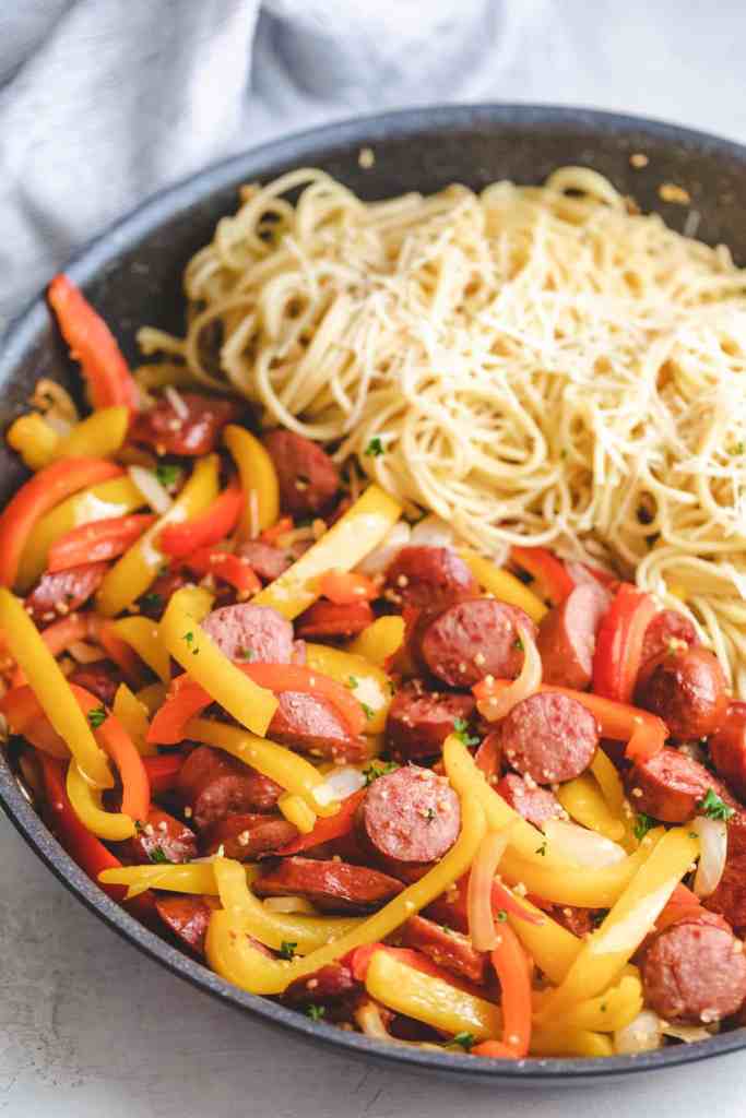 Kielbasa with onions and peppers cooked in a skillet for a quick summer dinner.