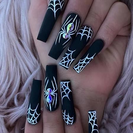 Matte black nails featuring intricate white spiderweb designs and decorative jeweled spiders, creating a bold Halloween statement.