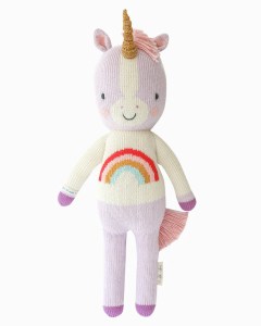 A soft, pastel-colored knit unicorn doll with a rainbow design on its body and a cute smile.