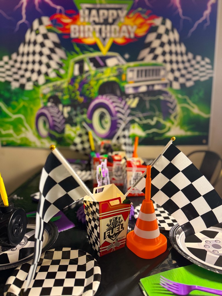 Monster truck birthday party decorations with checkered racing flags, traffic cone decor, and Monster Jam themed party table setup.