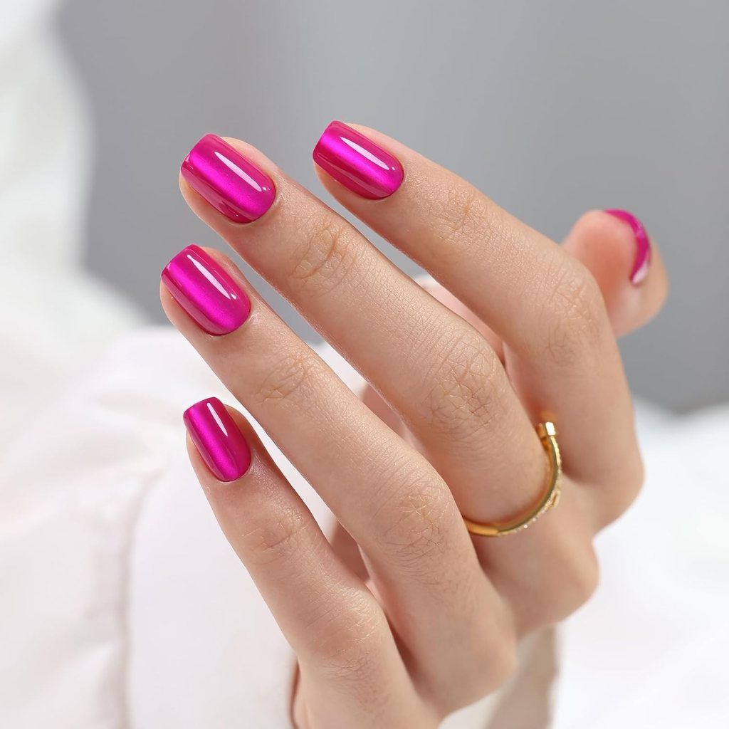 A close-up of a hand with shiny pink nail polish and a gold ring on one finger.