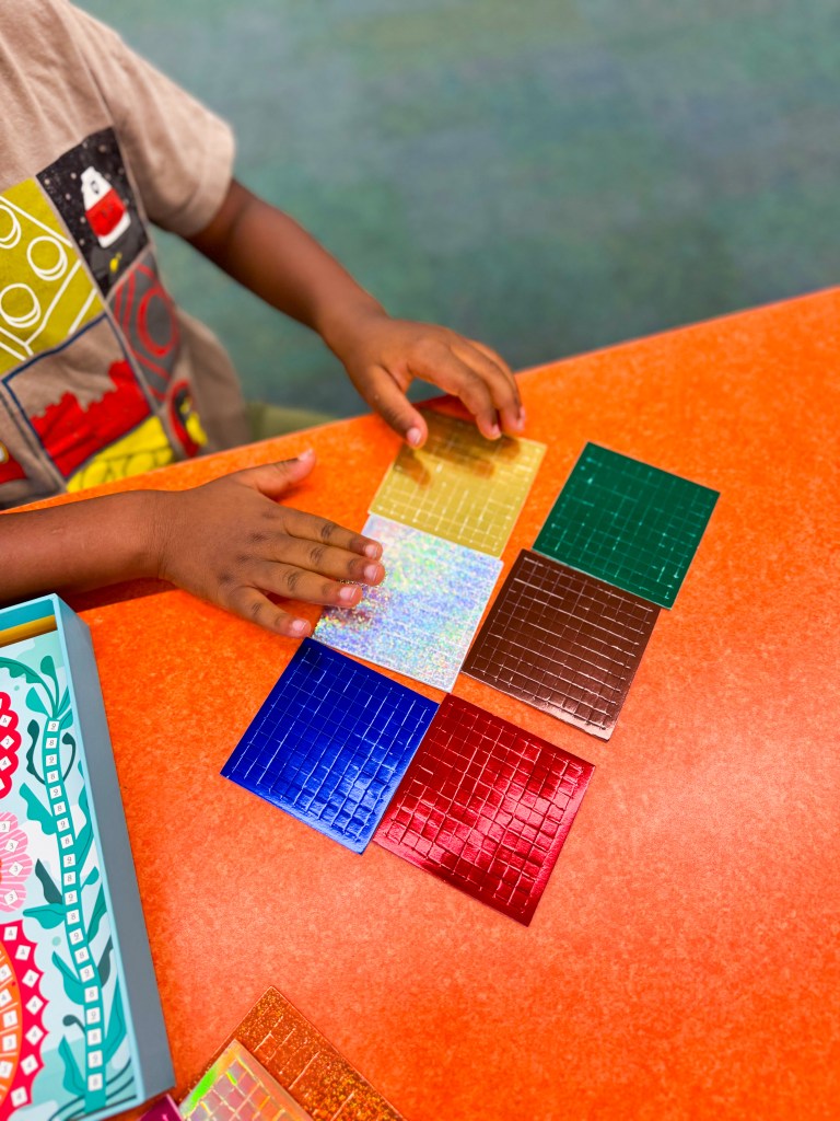 Child exploring colorful metallic mosaic stickers used in the Djeco Caribbean Mosaics activity.