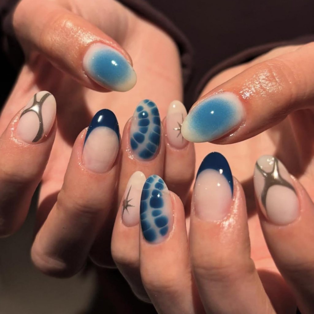 Airbrush blue aura almond nails with chrome silver accents, soft blue gradients, and abstract nail art.