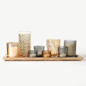 A collection of decorative candles in various shapes and sizes, arranged on a wooden tray, creating an elegant centerpiece.