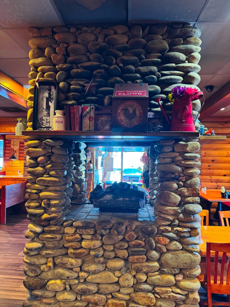 Rustic river stone fireplace decorated with antique farmhouse memorabilia inside Flapjack's Pancake Cabin.