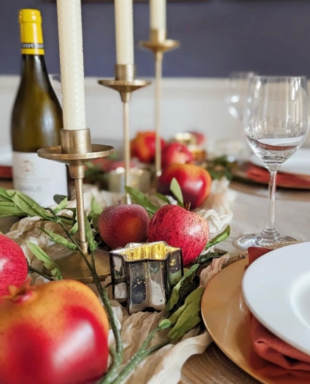 A beautifully set fall table featuring red apples, candles, and elegant glassware, creating a cozy and inviting dining atmosphere.