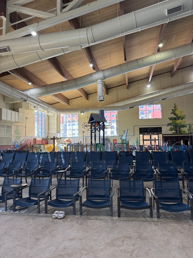 Indoor seating area at Great Wolf Lodge featuring rows of blue lounge chairs and a visible water play area in the background.