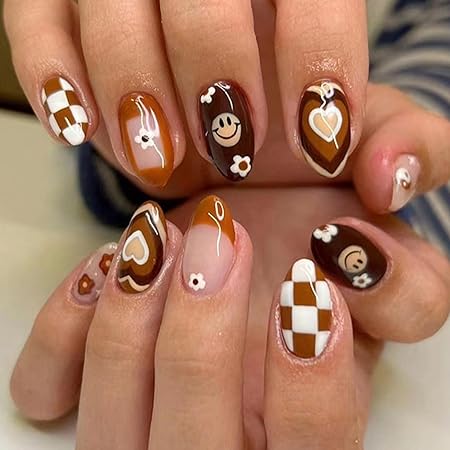 A close-up of manicured nails featuring a warm, autumn color palette with designs including hearts, smiley faces, and a checkerboard pattern in brown, white, and orange tones.