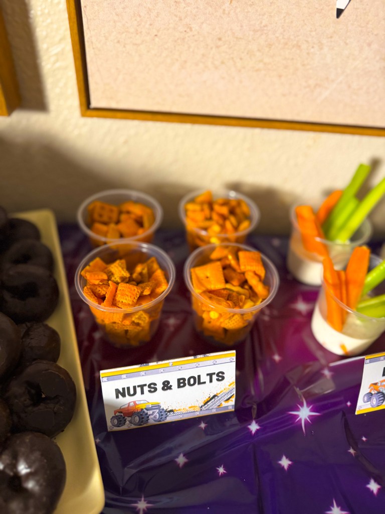 Monster truck birthday party snack idea called nuts and bolts made with Chex mix served in cups on a racing themed snack table.