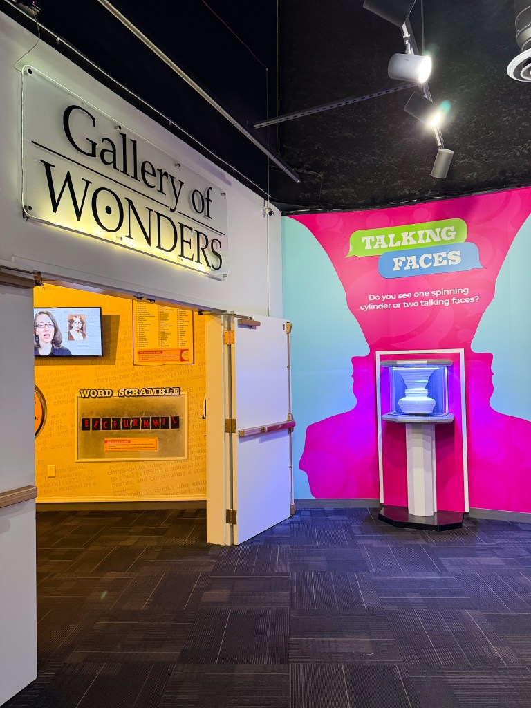 Entrance to the Gallery of Wonders featuring a sign, interactive exhibits, and colorful wall displays.