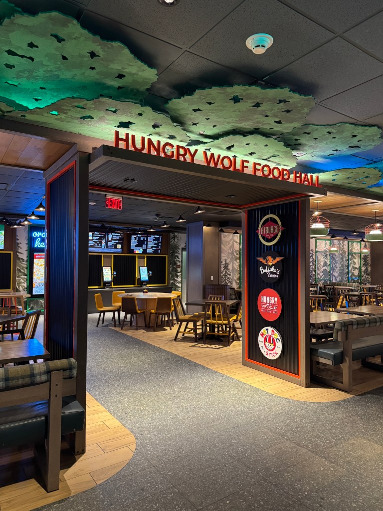 Entrance to the Hungry Wolf Food Hall featuring a forest-themed decor and seating areas.