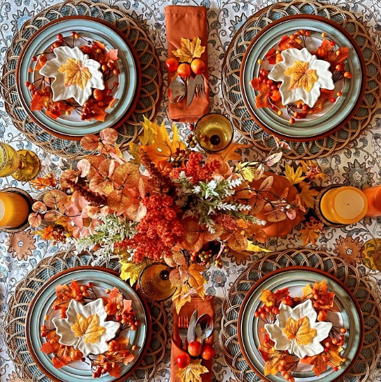 An autumn-themed tablescape featuring earthy tones, seasonal decorations, and intricate place settings with leaf motifs and floral arrangements, creating a cozy and inviting atmosphere.