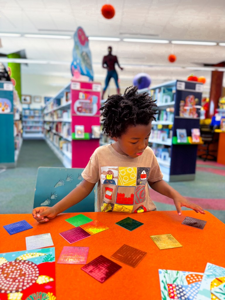 Kindergartner concentrating on colorful mosaic materials during a quiet hands-on learning activity.