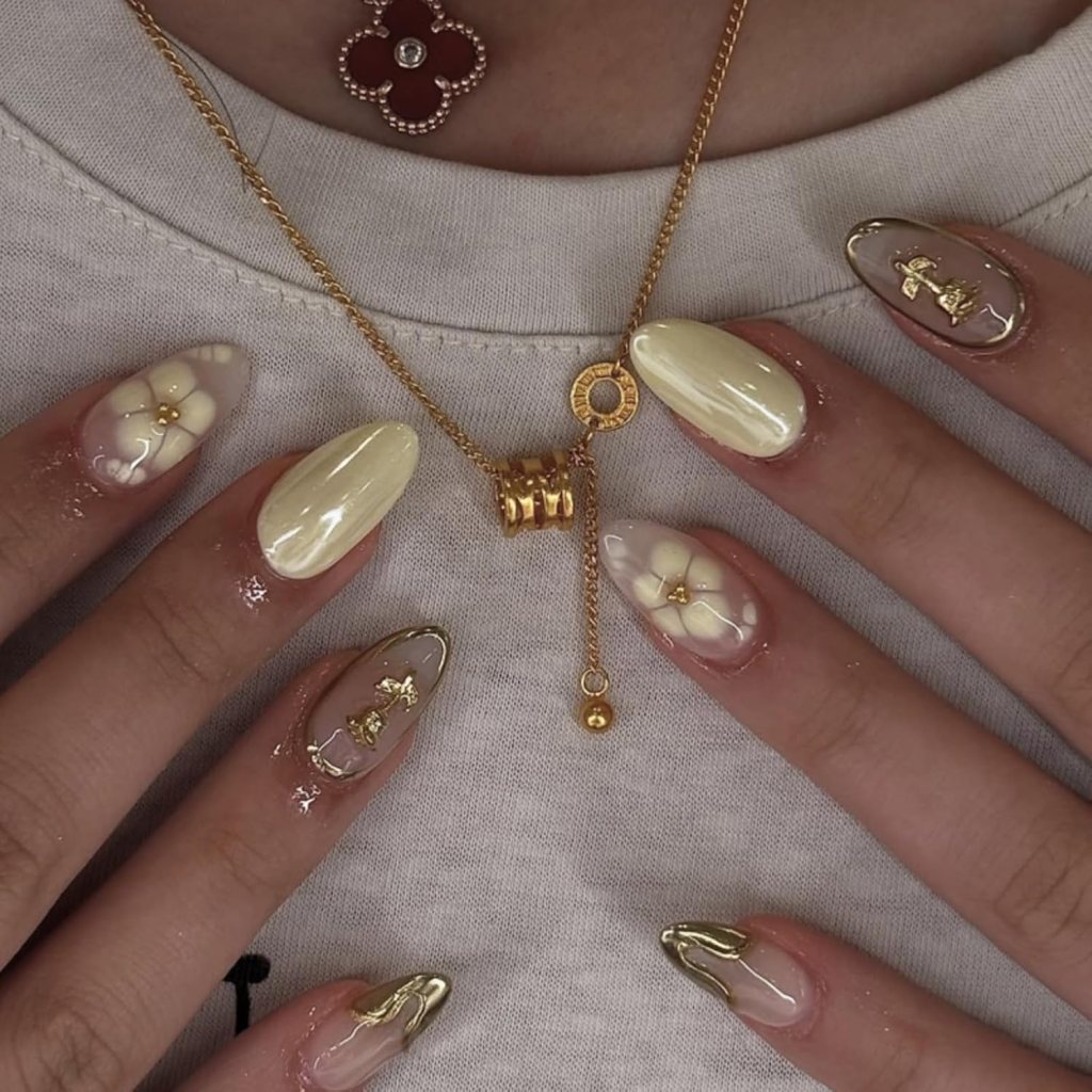 Butter yellow minimalist nails with gold accent details and glossy almond shaped manicure aesthetic