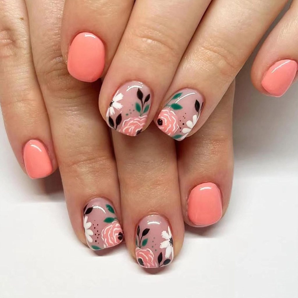 Close-up of manicured nails featuring a coral pink polish and intricate floral designs in pink, white, and green on select nails.