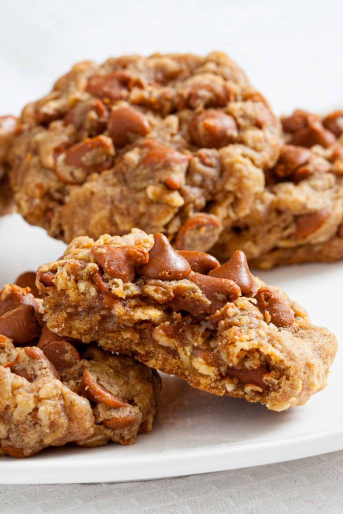 Close-up of chewy cookies loaded with chocolate chips on a white plate, showcasing a rich and inviting texture.