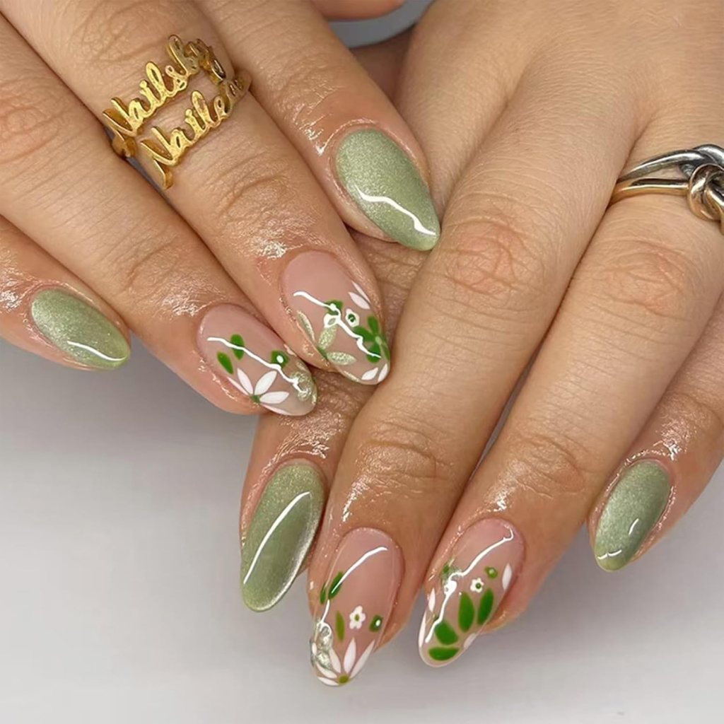 A close-up of manicured hands displaying green and nude nail designs, featuring floral patterns with white and green accents, and a gold 'Nails by Natilee' ring.