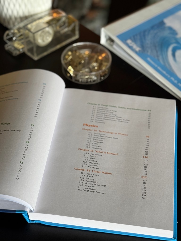 An open textbook displaying the table of contents, including chapters on technology in physics and various scientific concepts, with a blue cover partially visible in the background.