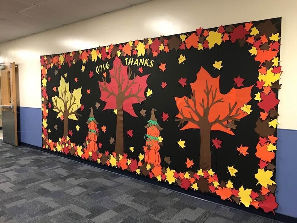 Large Give Thanks fall bulletin board decorated with autumn trees, stacked pumpkins and red, orange and yellow leaves.