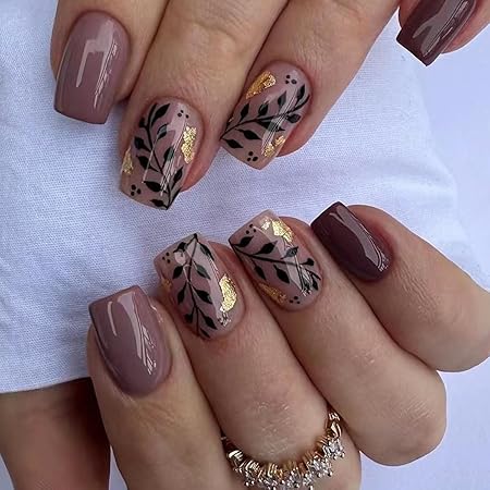 A close-up view of elegantly manicured nails featuring a mix of soft mauve and brown tones, adorned with delicate leaf patterns in black and gold accents.