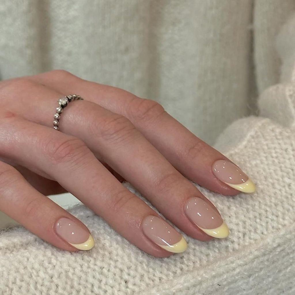 Butter yellow minimal French tip short nails with glossy nude base and clean pastel manicure design
