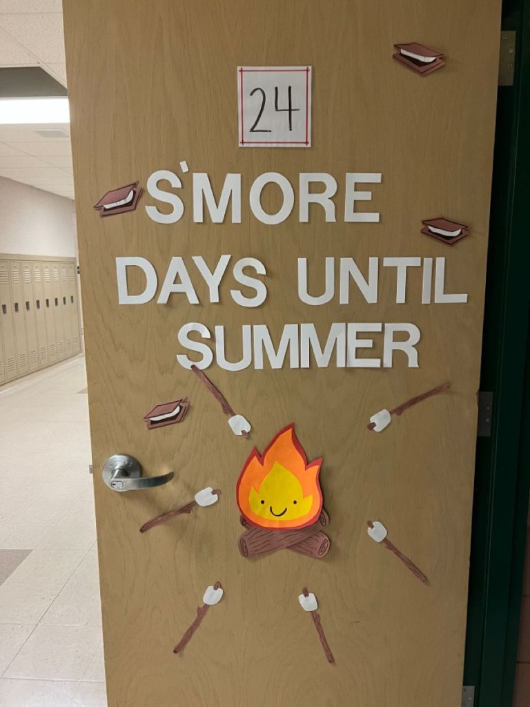 Wooden door decorated with a countdown sign reading '24 S'more Days Until Summer,' featuring illustrations of marshmallows, a campfire, and graham crackers.