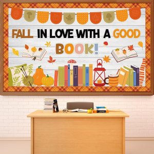 A colorful classroom bulletin board featuring the phrase 'FALL IN LOVE WITH A GOOD BOOK!' with illustrations of autumn leaves, pumpkins, books, and a lantern.