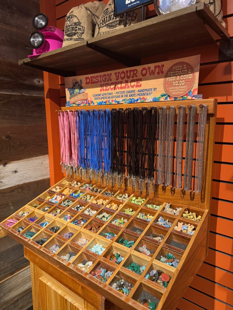 Display of various colorful gemstones and cords for designing custom necklaces at Great Wolf Lodge's Oliver's Mining Co.