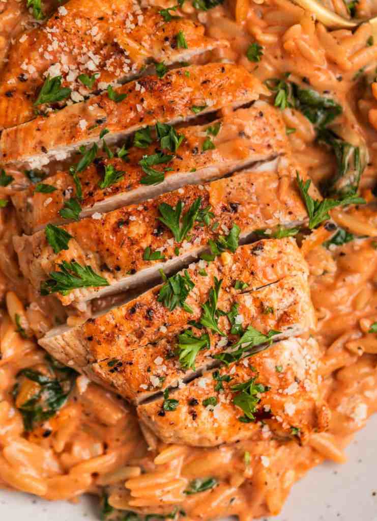 Sliced cooked chicken breast topped with fresh parsley, served over creamy orzo pasta.