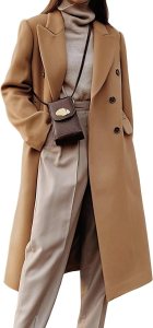 A woman wearing a long camel coat over a fitted turtleneck and wide-leg trousers, complemented by a small crossbody bag.
