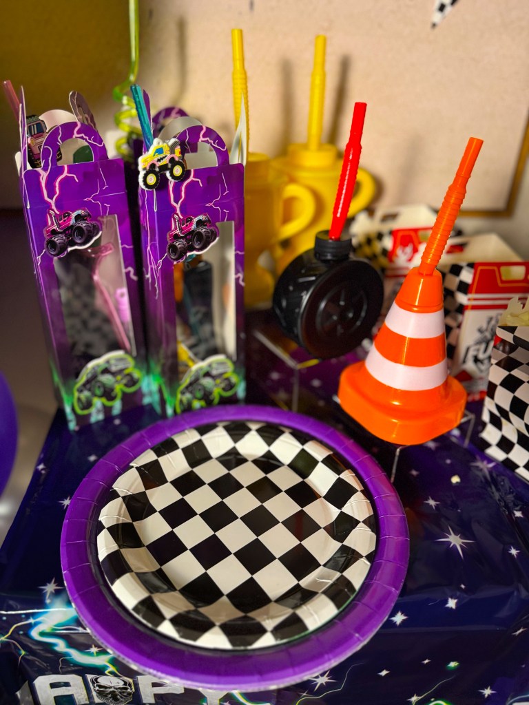 Monster Jam birthday party table setup with racing themed plates, monster truck party favors, and traffic cone drink cup.