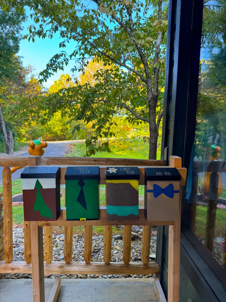 Colorful mailbox decorations featuring four themed designs, including 'You Bear', 'Ranger Smith', 'Candy Bear', and 'Boo Boo', set against a backdrop of trees and blue sky.