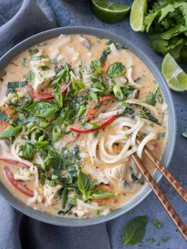 Spicy Thai red curry soup with coconut milk, vegetables, and fresh herbs served in a rustic bowl