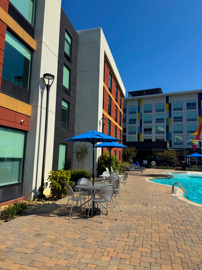 Poolside tables, chairs and umbrellas beside the outdoor pool at Home2 Suites Pigeon Forge.