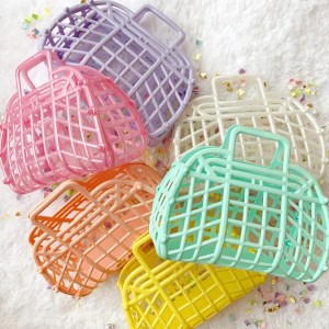 A collection of colorful plastic baskets in pastel shades, including pink, lavender, mint green, white, orange, and yellow, arranged on a white surface sprinkled with confetti.