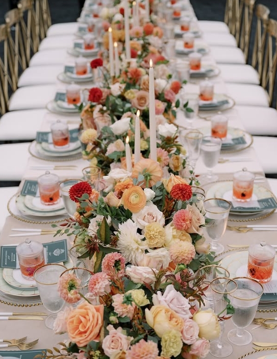 A beautifully styled Thanksgiving table adorned with a vibrant floral centerpiece, taper candles, and elegant dinnerware, creating a warm and inviting atmosphere.