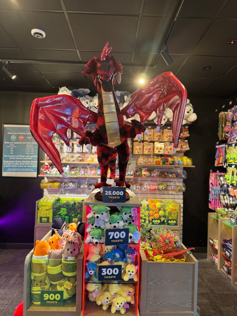 Prize redemption display at Northern Lights Arcade in Great Wolf Lodge Grapevine featuring a large dragon plush and ticket prizes.