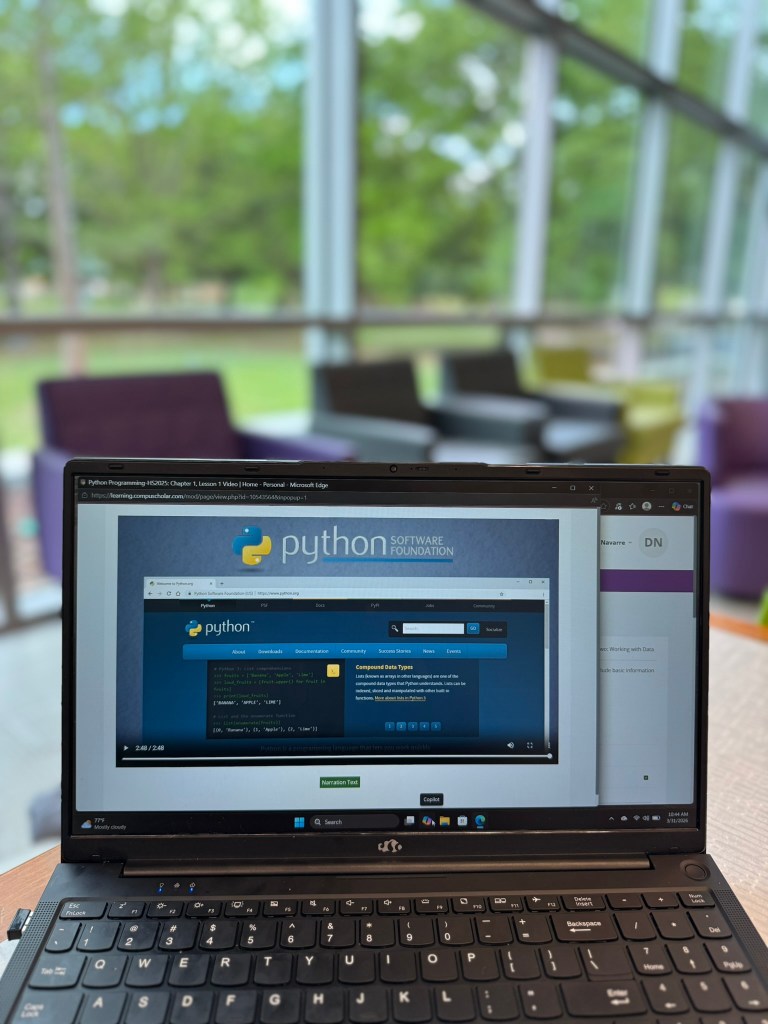 Wide shot of CompuScholar Python course video lesson on laptop with homeschool workspace background