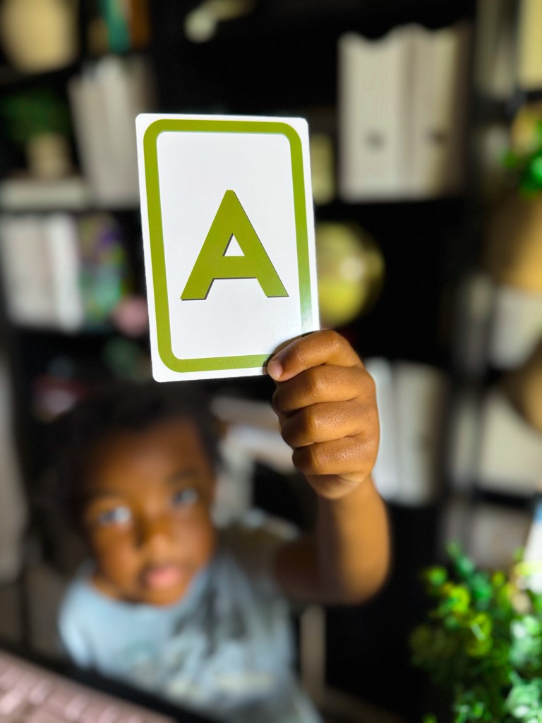 Child holding an uppercase letter A flashcard during kindergarten letter recognition practice