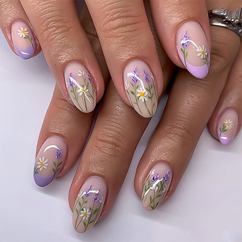 Close-up of elegantly manicured hands with floral nail art featuring purple and white flowers on a nude background.