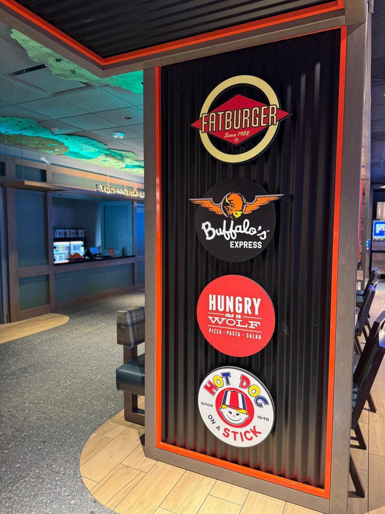 Signage for various dining options inside Great Wolf Lodge, featuring logos for Fatburger, Buffalo's Express, Hungry as a Wolf, and Hot Dog on a Stick.