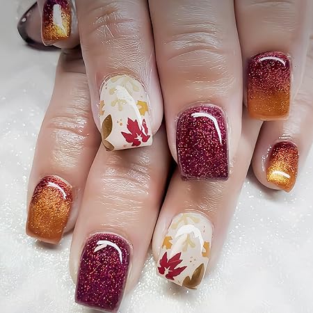 Close-up of beautifully manicured nails featuring autumn-inspired designs with rich burgundy and orange glitter polish, complemented by leaves in warm colors on a nude base.