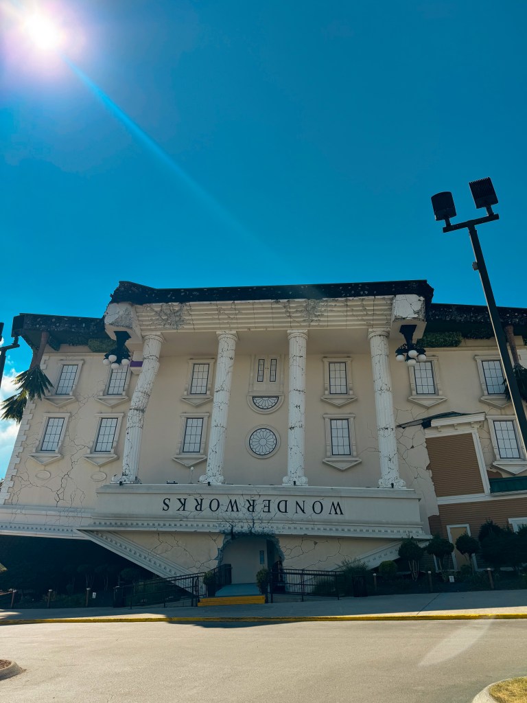 Upside-down building named WonderWorks with columns and a cracked exterior under a clear blue sky.