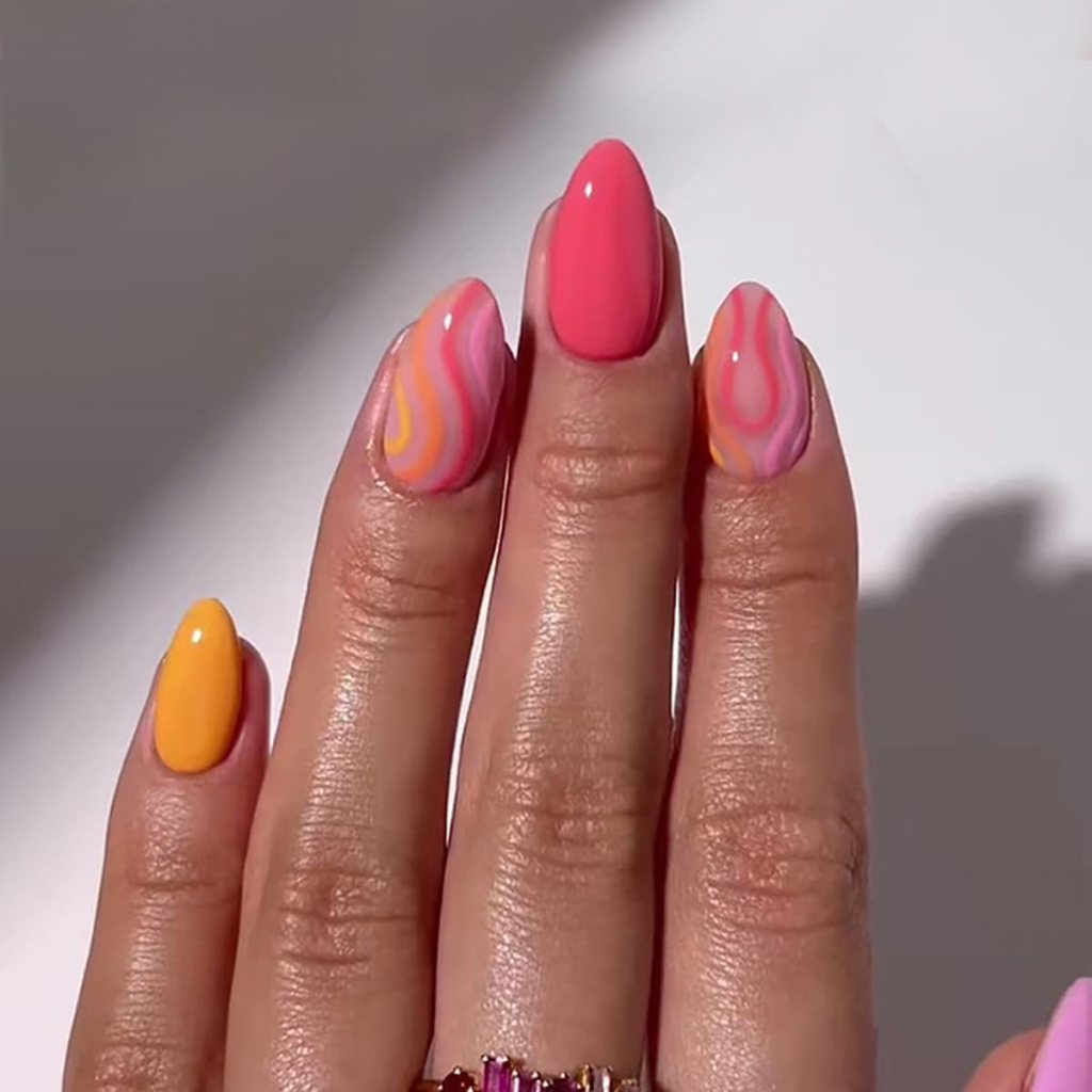 A hand with manicured nails featuring a mix of pink, orange, and yellow designs, including a marbled pattern on some nails.