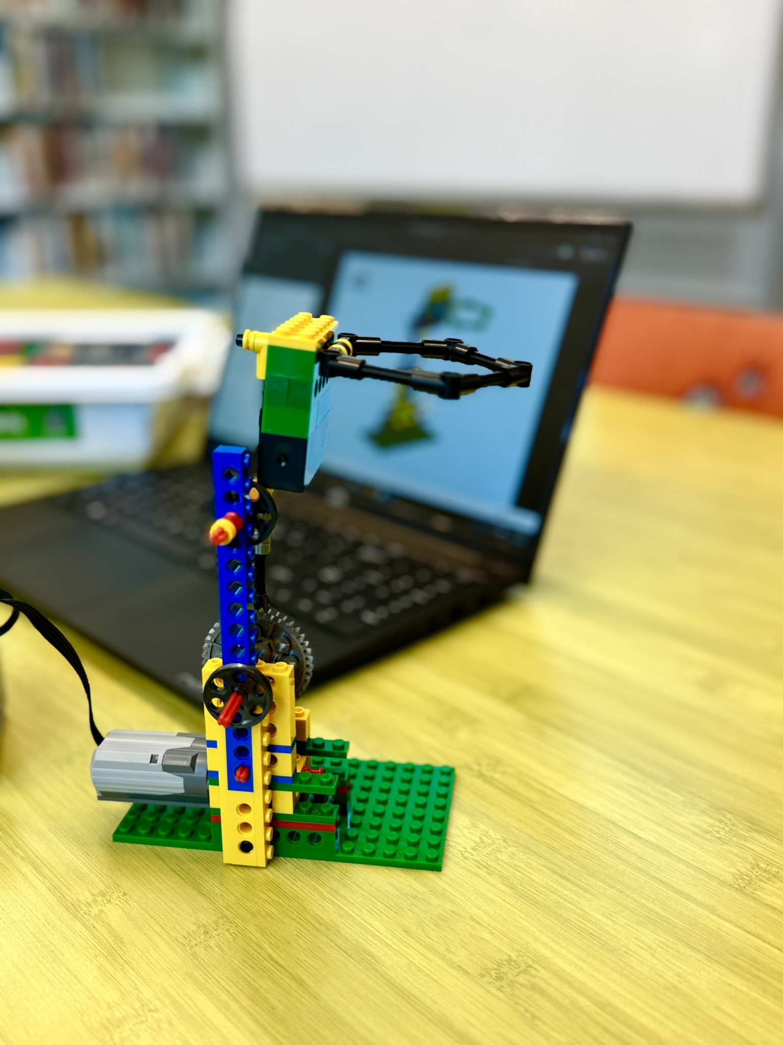 LEGO structure with a motor on a table in front of a laptop displaying LEGO building instructions