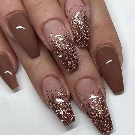 A manicure featuring long almond-shaped nails in a soft brown color with glittery rose gold tips, creating a glamorous ombré effect.