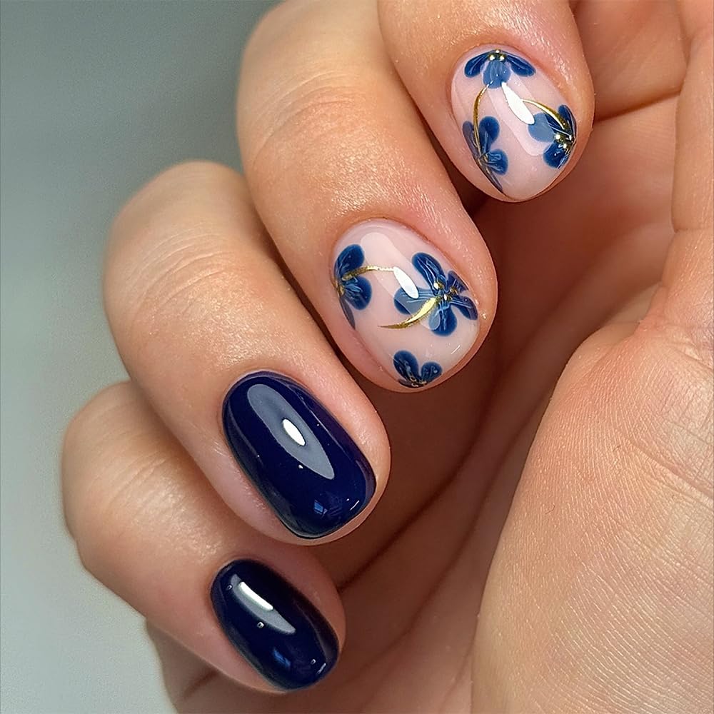 Navy blue floral short nails with glossy dark blue polish and delicate blue flower nail art on nude nails.