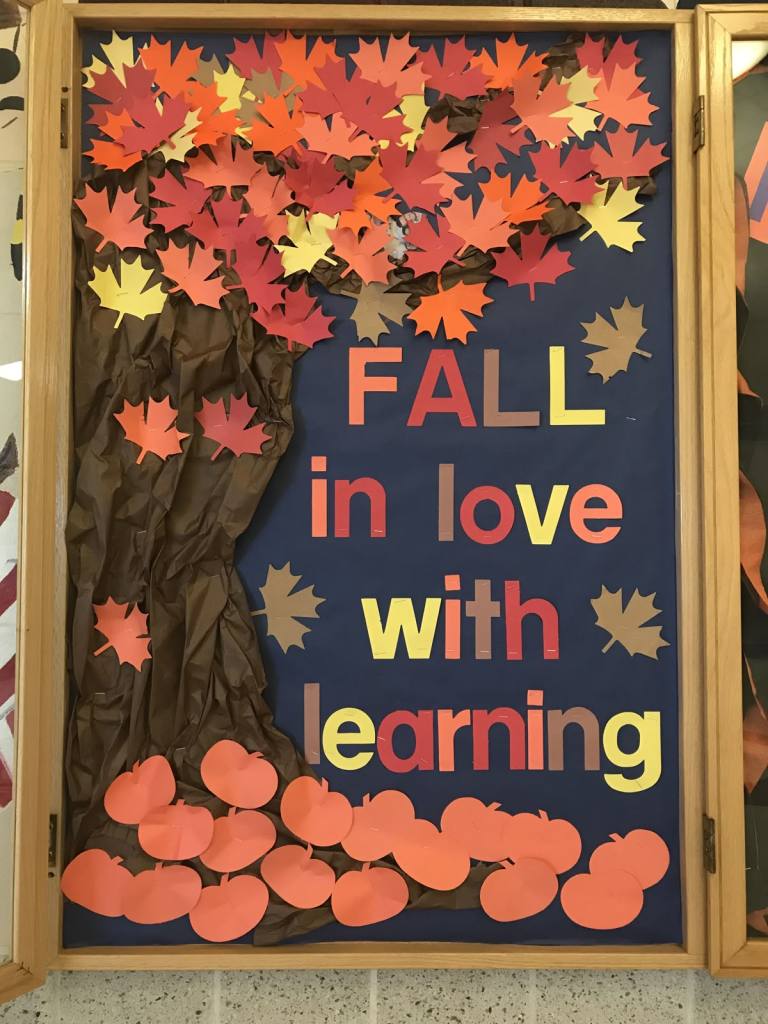 Fall in Love With Learning bulletin board featuring dimensional orange pumpkins, green vines and autumn leaves on a blue background.